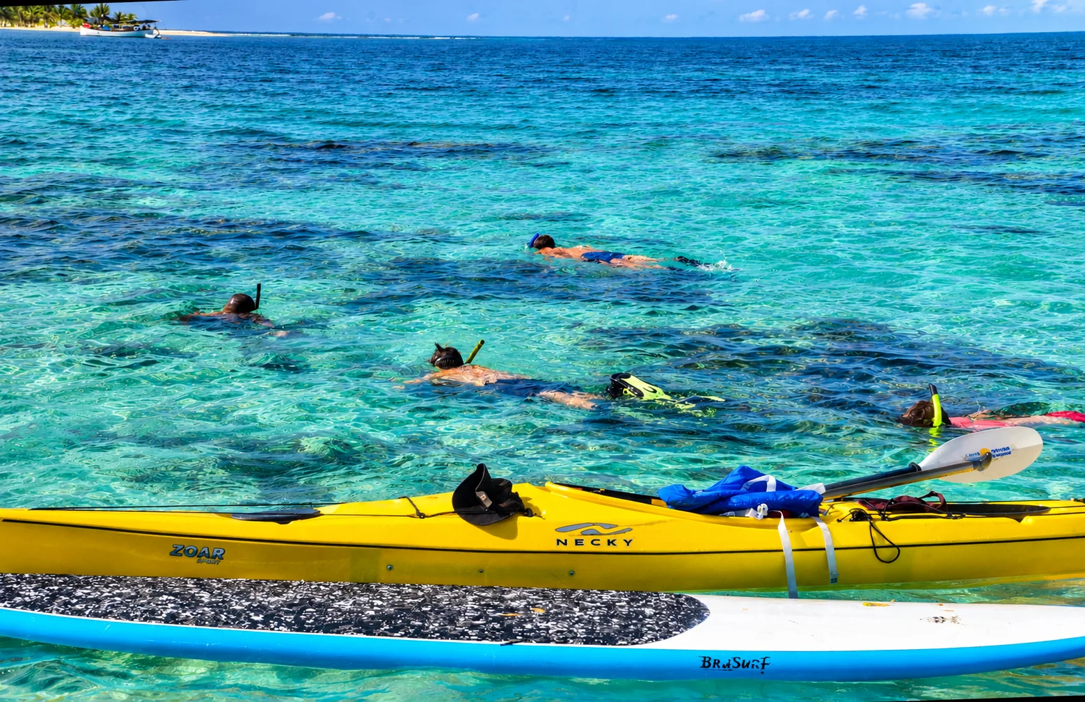 Snorkelers beside kayaks in clear water